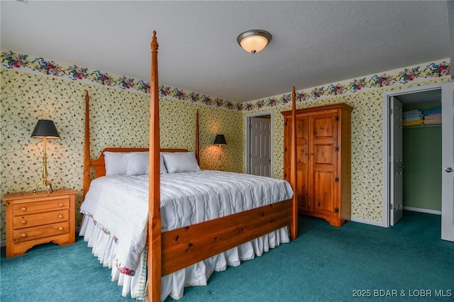 bedroom with a closet, a spacious closet, a textured ceiling, and dark colored carpet