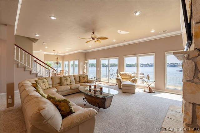 living room with a water view, light colored carpet, crown molding, and ceiling fan with notable chandelier