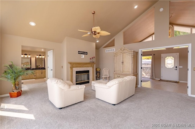 unfurnished living room featuring ceiling fan, light colored carpet, a high end fireplace, and high vaulted ceiling