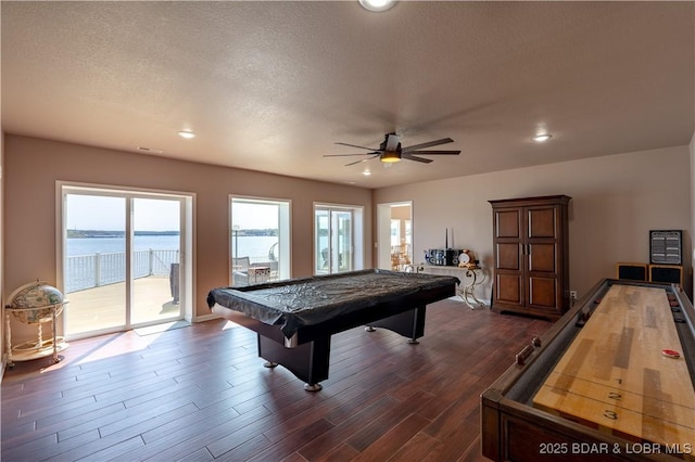 rec room featuring ceiling fan, a water view, a textured ceiling, dark hardwood / wood-style flooring, and pool table