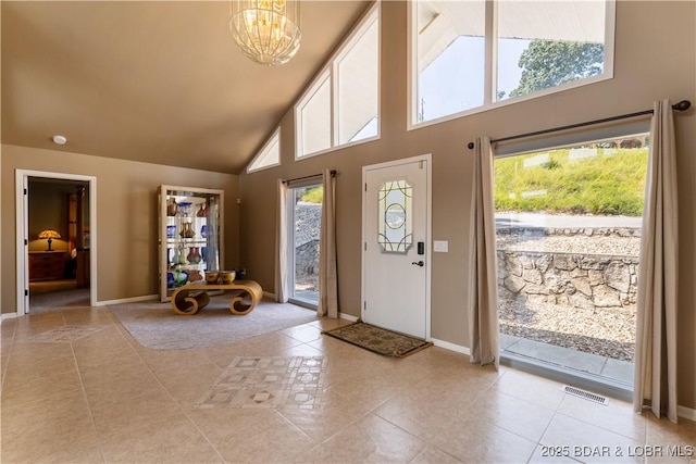 tiled foyer entrance featuring plenty of natural light, a chandelier, and high vaulted ceiling