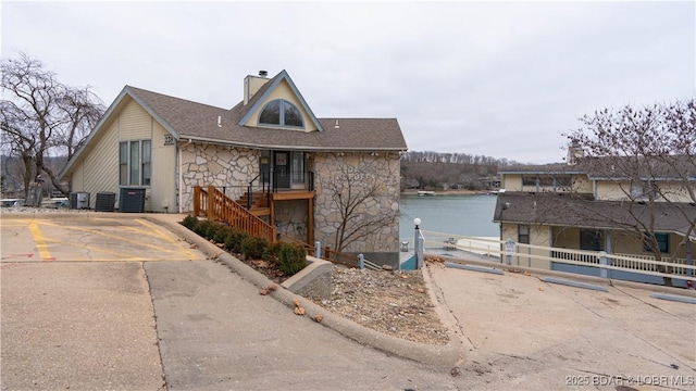 view of front of home featuring central AC unit and a water view