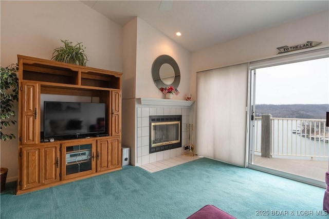 unfurnished living room featuring a tile fireplace, vaulted ceiling, and light colored carpet