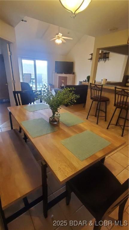 dining room featuring vaulted ceiling, tile patterned floors, and ceiling fan