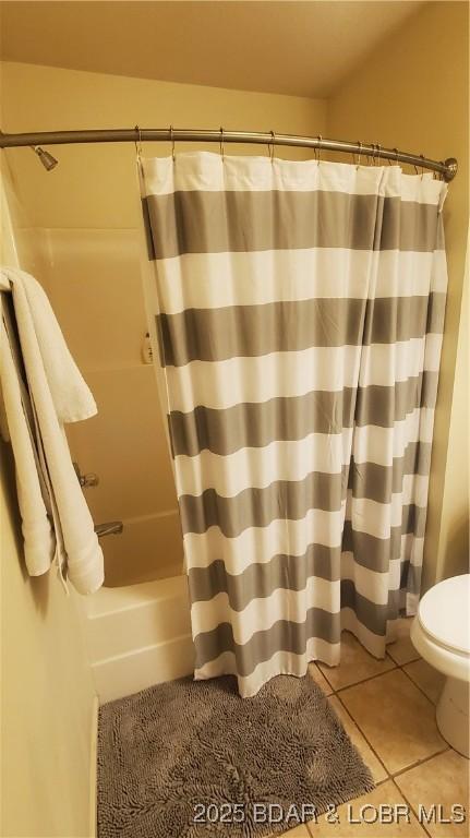 bathroom featuring tile patterned flooring, toilet, and shower / bathtub combination with curtain