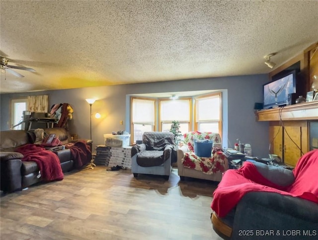 living room featuring hardwood / wood-style flooring, ceiling fan, plenty of natural light, and a textured ceiling