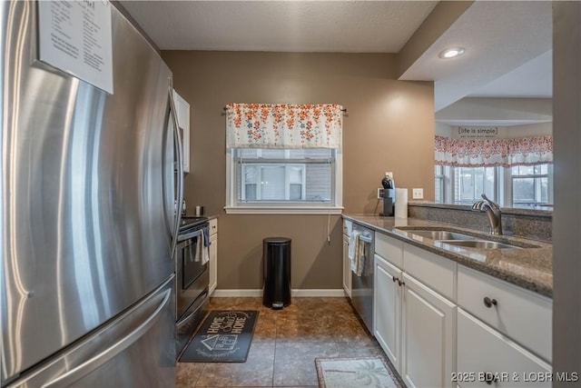 kitchen featuring stainless steel appliances, white cabinetry, sink, and dark stone countertops