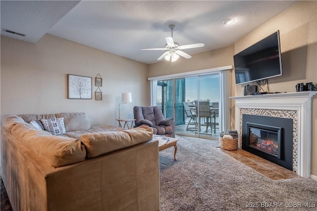 tiled living room featuring ceiling fan and a fireplace