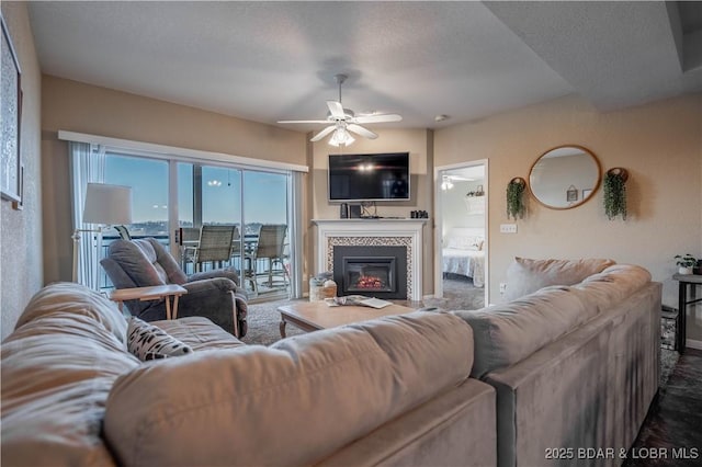 living room with ceiling fan, a fireplace, and a textured ceiling