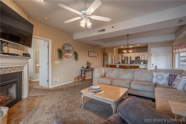 living room featuring a tiled fireplace, light colored carpet, a raised ceiling, and ceiling fan