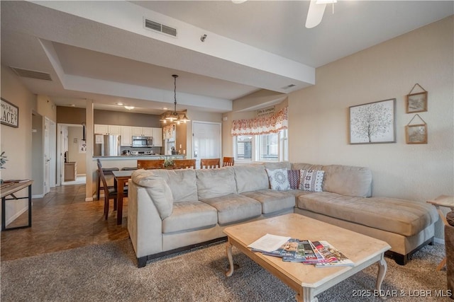 living room featuring ceiling fan with notable chandelier and dark tile patterned floors