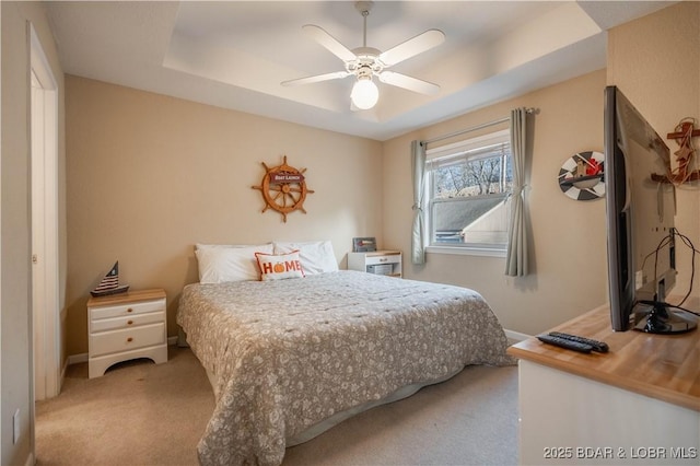 bedroom featuring light colored carpet, a raised ceiling, and ceiling fan