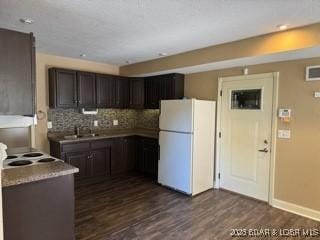 kitchen with tasteful backsplash, white appliances, dark wood-type flooring, and dark brown cabinets