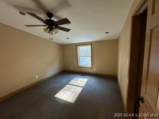 spare room with dark carpet and ceiling fan