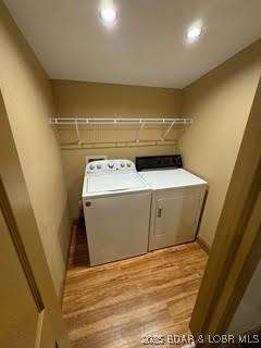 clothes washing area with independent washer and dryer and light wood-type flooring