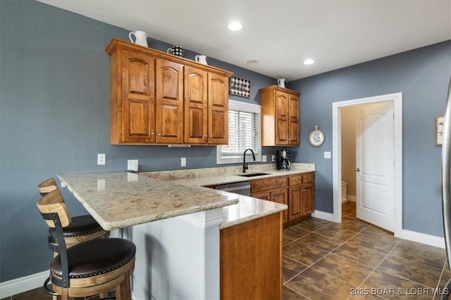 kitchen featuring sink, a breakfast bar area, dark tile patterned flooring, kitchen peninsula, and light stone countertops