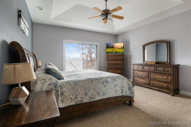 bedroom with ceiling fan, a tray ceiling, and carpet