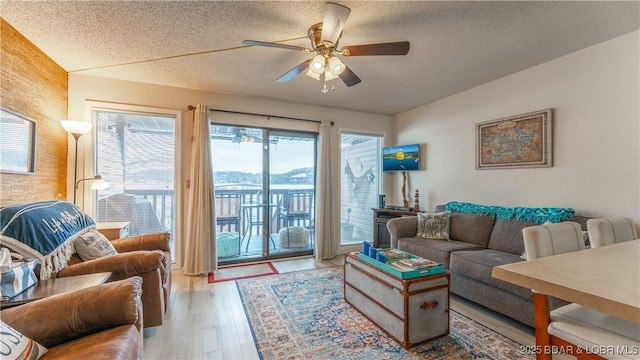 living room with wood-type flooring, ceiling fan, and a textured ceiling