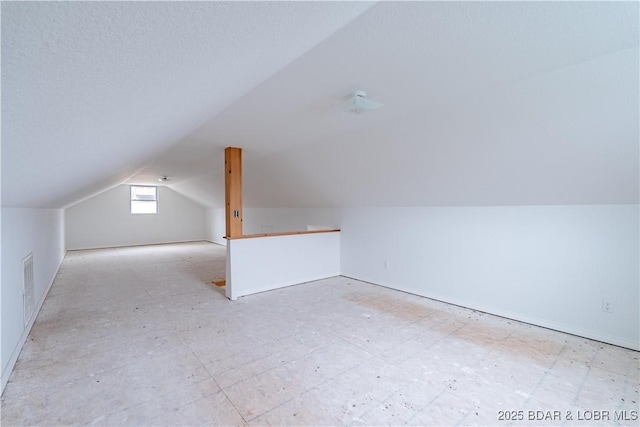 bonus room with vaulted ceiling and a textured ceiling