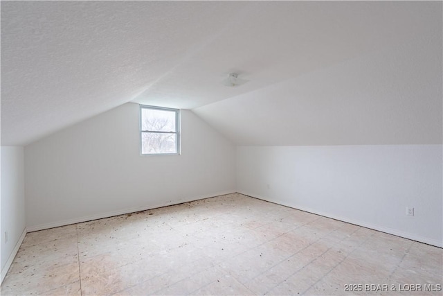 bonus room with vaulted ceiling and a textured ceiling