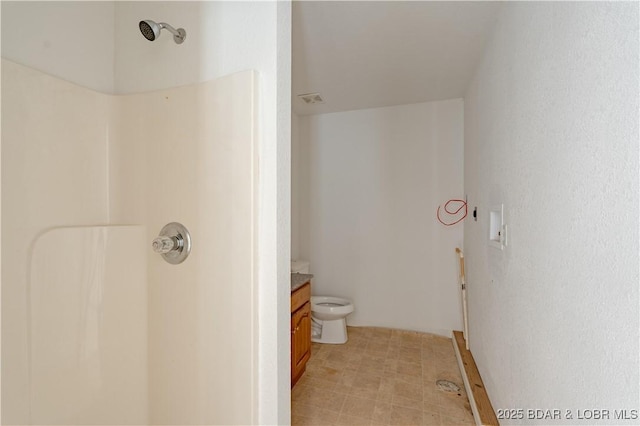 bathroom featuring vanity, a shower, and toilet