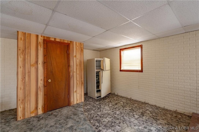 basement with brick wall and a drop ceiling