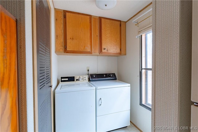 clothes washing area with cabinets and washing machine and clothes dryer