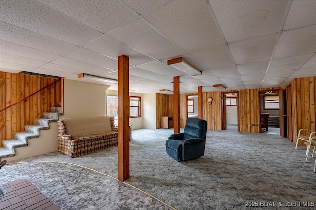 interior space featuring a paneled ceiling, carpet floors, and wood walls