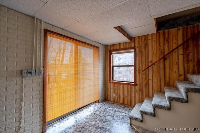 doorway featuring a drop ceiling and wood walls