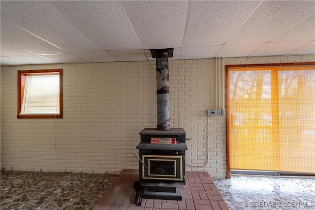 interior space with a wood stove and a drop ceiling