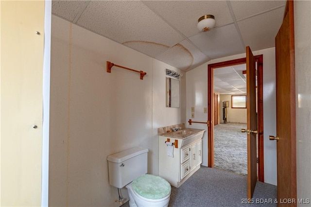 bathroom featuring vanity, toilet, and a drop ceiling