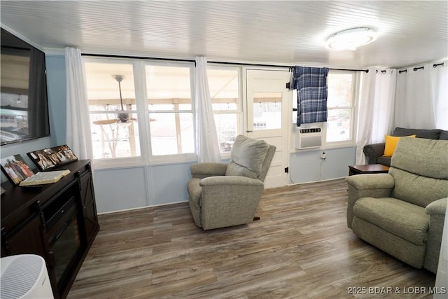 living room featuring cooling unit, wood-type flooring, and a wealth of natural light