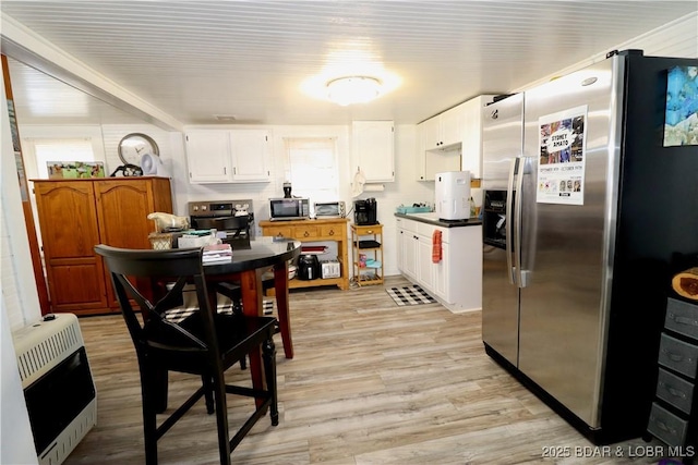 kitchen featuring white cabinetry, appliances with stainless steel finishes, heating unit, and light hardwood / wood-style floors