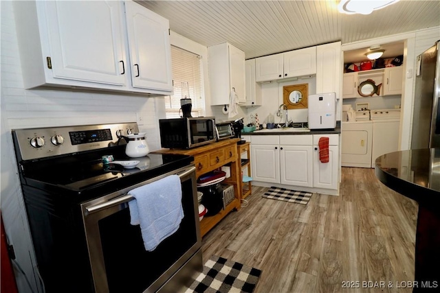 kitchen with white cabinetry, sink, washing machine and clothes dryer, and appliances with stainless steel finishes