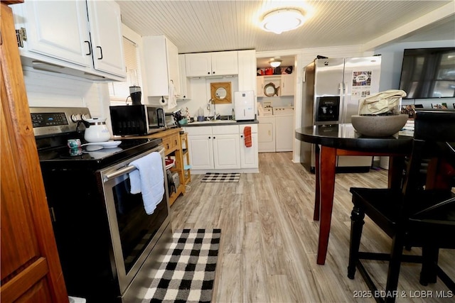 kitchen with stainless steel electric stove, washer and dryer, white cabinetry, sink, and light wood-type flooring