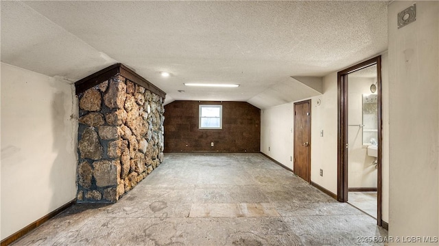 additional living space featuring lofted ceiling and a textured ceiling