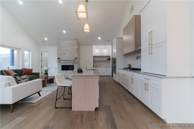 kitchen with pendant lighting, an island with sink, and white cabinets