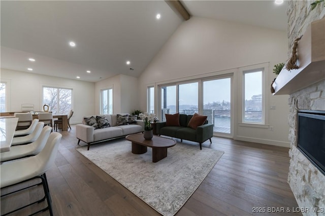 living room with dark hardwood / wood-style flooring, a stone fireplace, high vaulted ceiling, and beamed ceiling