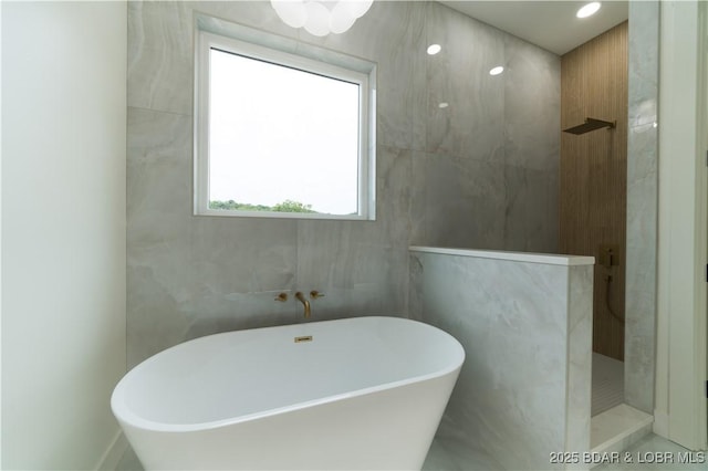 bathroom featuring plus walk in shower and tile walls