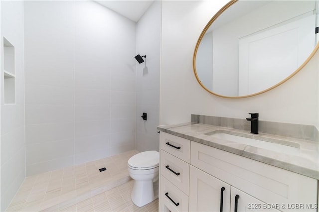 bathroom with vanity, a tile shower, and toilet