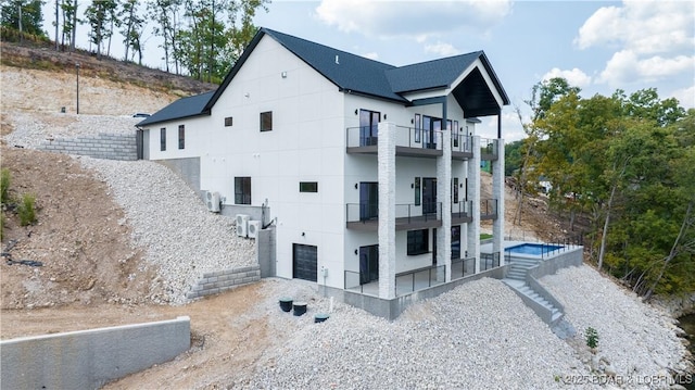 view of property exterior featuring a balcony, a garage, and a hot tub