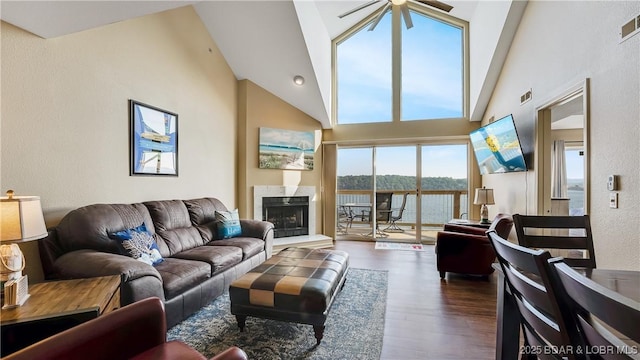 living room featuring ceiling fan, high vaulted ceiling, dark wood-type flooring, and a high end fireplace