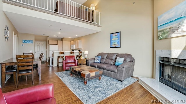 living room featuring a high end fireplace, wood-type flooring, and a high ceiling