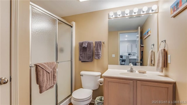 bathroom with an enclosed shower, vanity, and toilet