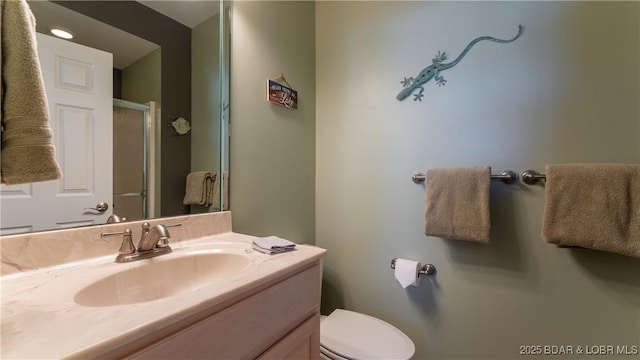 bathroom featuring vanity, toilet, and a shower with door