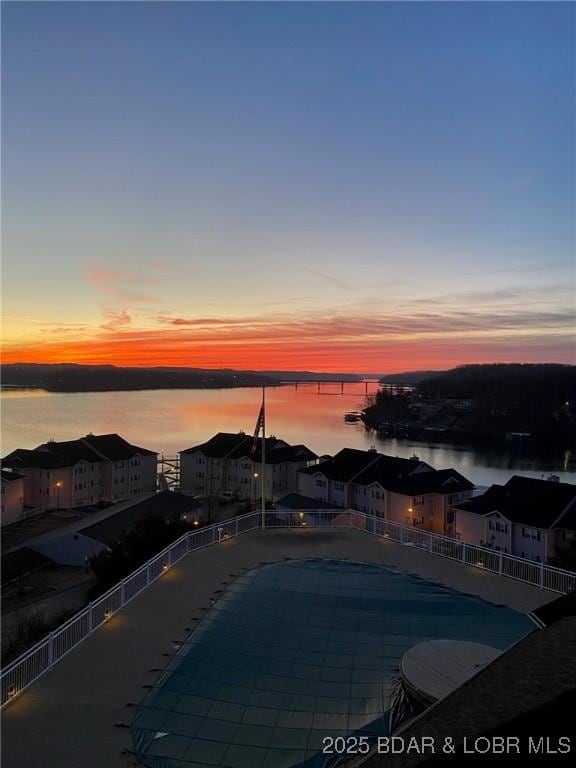 pool at dusk with a water view and a community pool