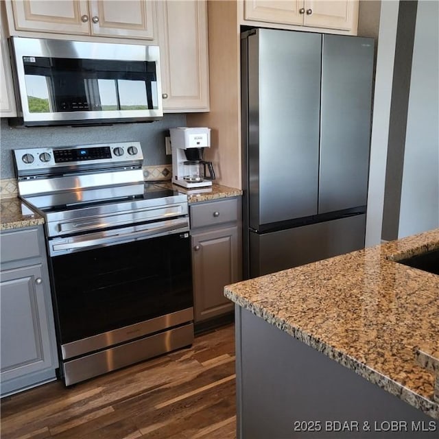 kitchen featuring gray cabinets, appliances with stainless steel finishes, white cabinets, dark hardwood / wood-style flooring, and light stone countertops