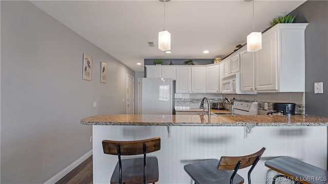 kitchen featuring white cabinetry, white appliances, decorative light fixtures, and kitchen peninsula