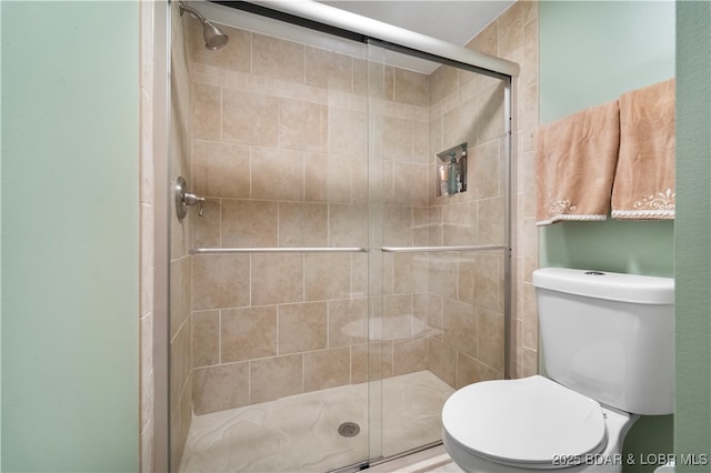 bathroom featuring toilet and a shower with shower door