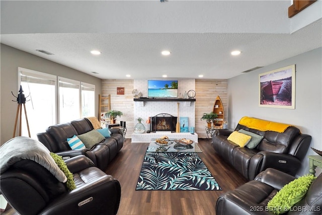 living room featuring dark wood-type flooring, a brick fireplace, and a textured ceiling